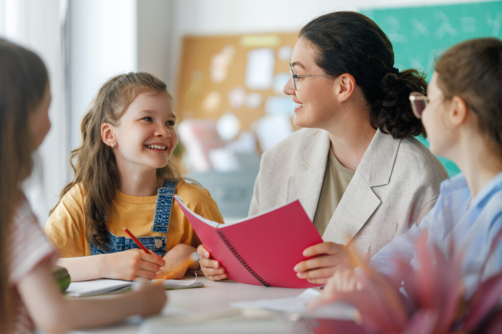 Happy kids and teacher at school. Woman and children are working in the class.