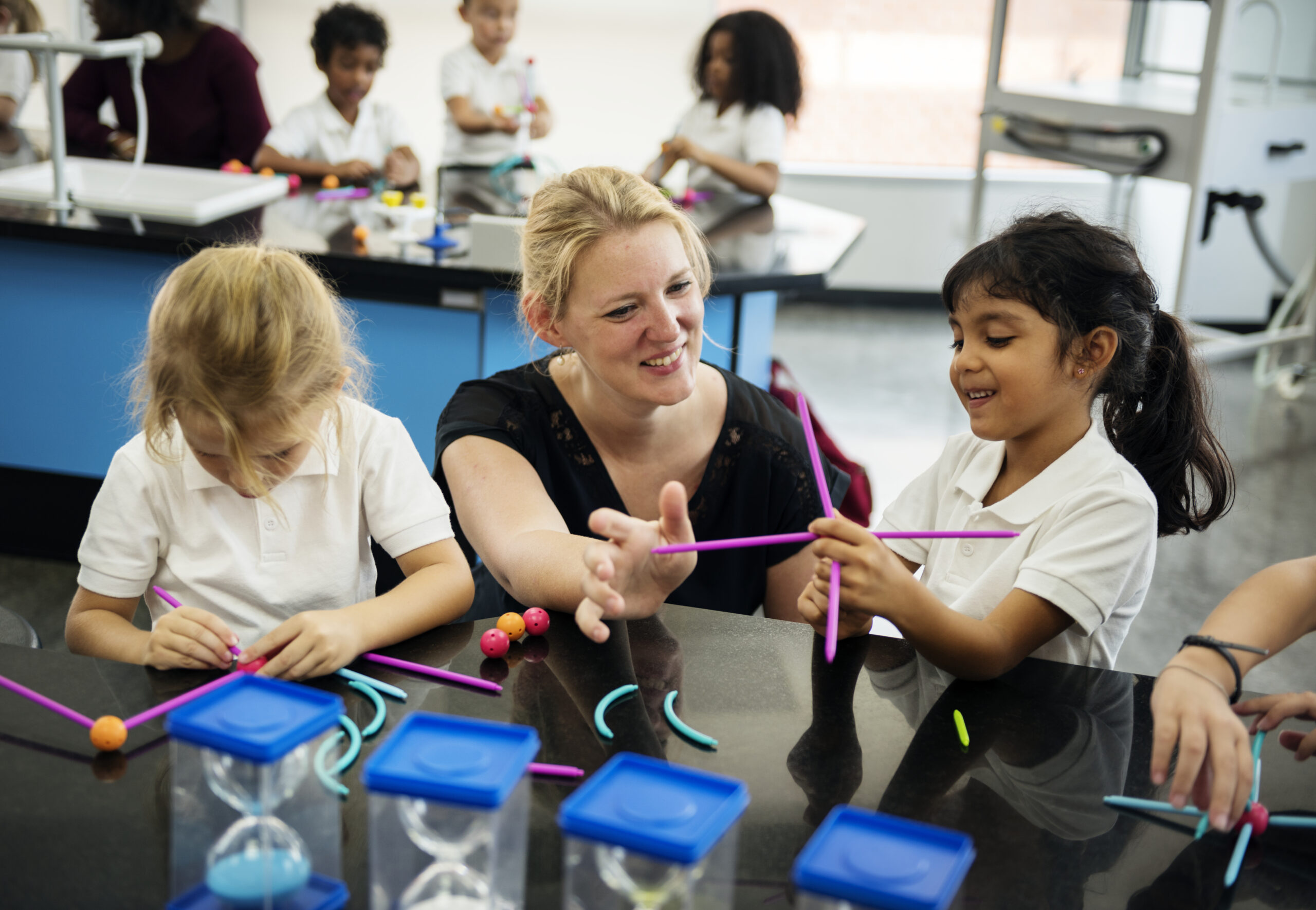 Happy kids at elementary school learning about science with their supply teacher
